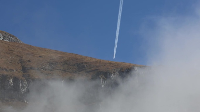 一架飞机在阿尔卑斯山峰的云层中消失