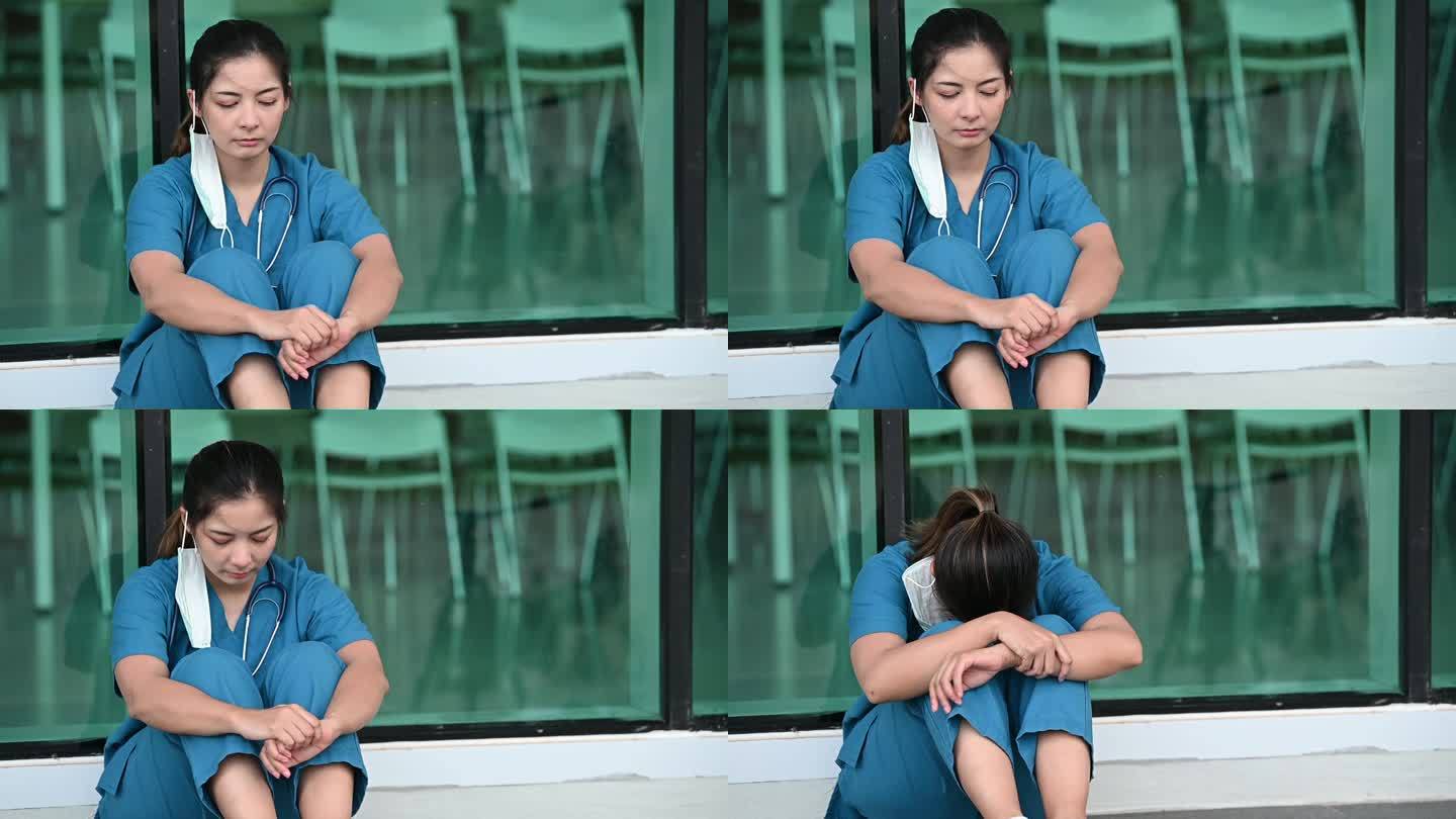 疲惫沮丧的亚洲女磨砂护士戴着口罩蓝色制服坐在医院地板上