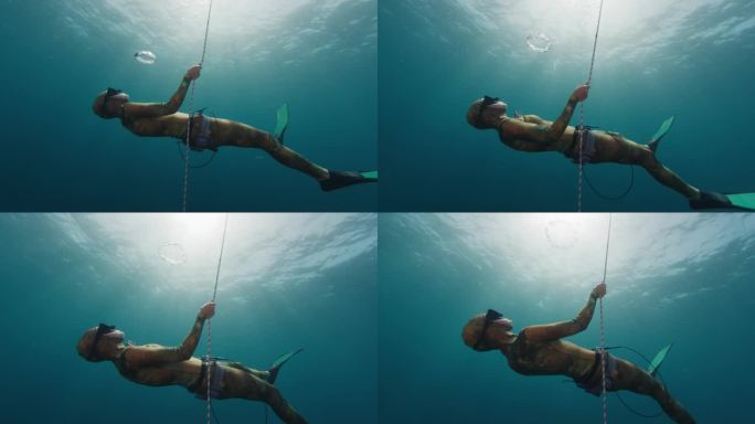 女自由潜水员在水下制造气泡环。女自由潜水员玩得很开心，并在深度上制造气泡环