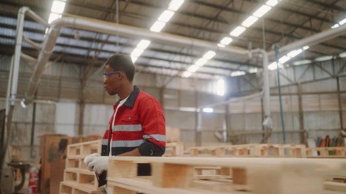 技术工人保证质量:非洲人在木棚检查库存托盘。