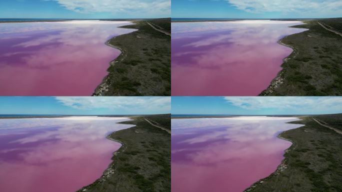 反向多丽鸟瞰图的赫特泻湖粉红湖的银行在西澳大利亚，靠近卡尔巴里。云层反射在湖面上，印度洋在蓝天和很少