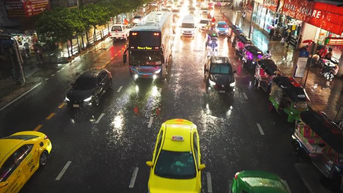 在一个雨夜的城市里，许多五颜六色的汽车和公共汽车行驶在潮湿的柏油路上。