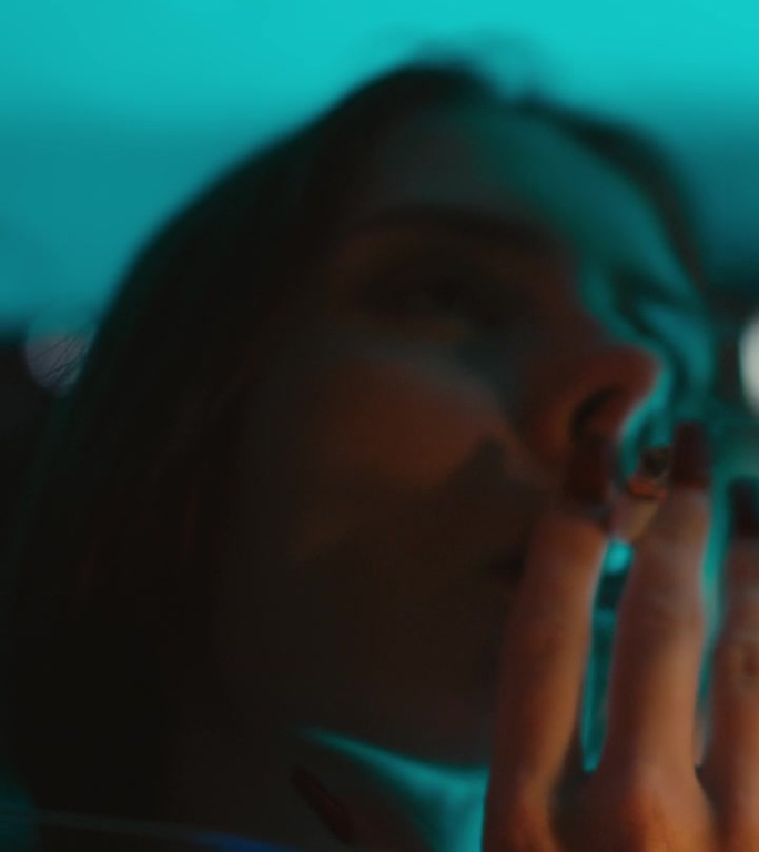夜间在车里吸烟的年轻迷人女子的垂直照片