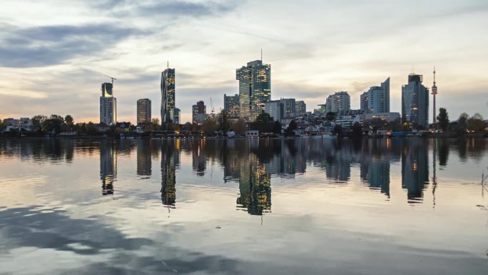 维也纳商业区的多瑙城(Donaustadt)的昼夜渐变天际线。平静的湖面上的倒影。