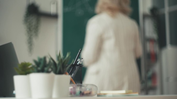 女教师在课堂上在黑板上写数学方程式的背影