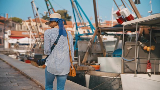 在克罗地亚村庄的港口码头上，女游客边走边拍照