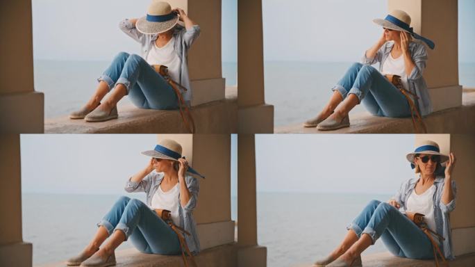 女游客戴着遮阳帽坐在克罗地亚海边柱廊的挡土墙上