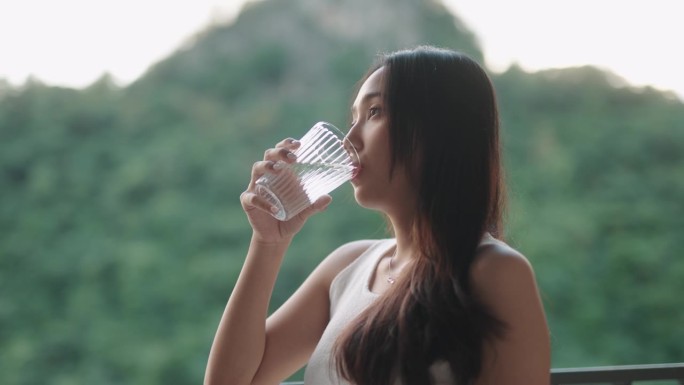 一个女人在喝水，背景是山景