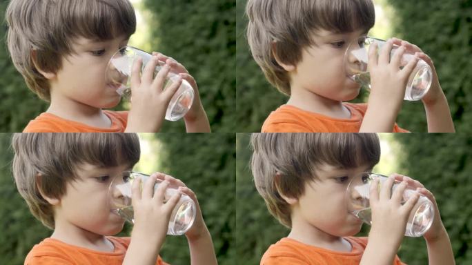 口渴的孩子在阳光照耀的户外喝玻璃水。小孩喝杯新鲜透明纯过滤水慢动作小孩喝杯水健康的身体护理健康的生活