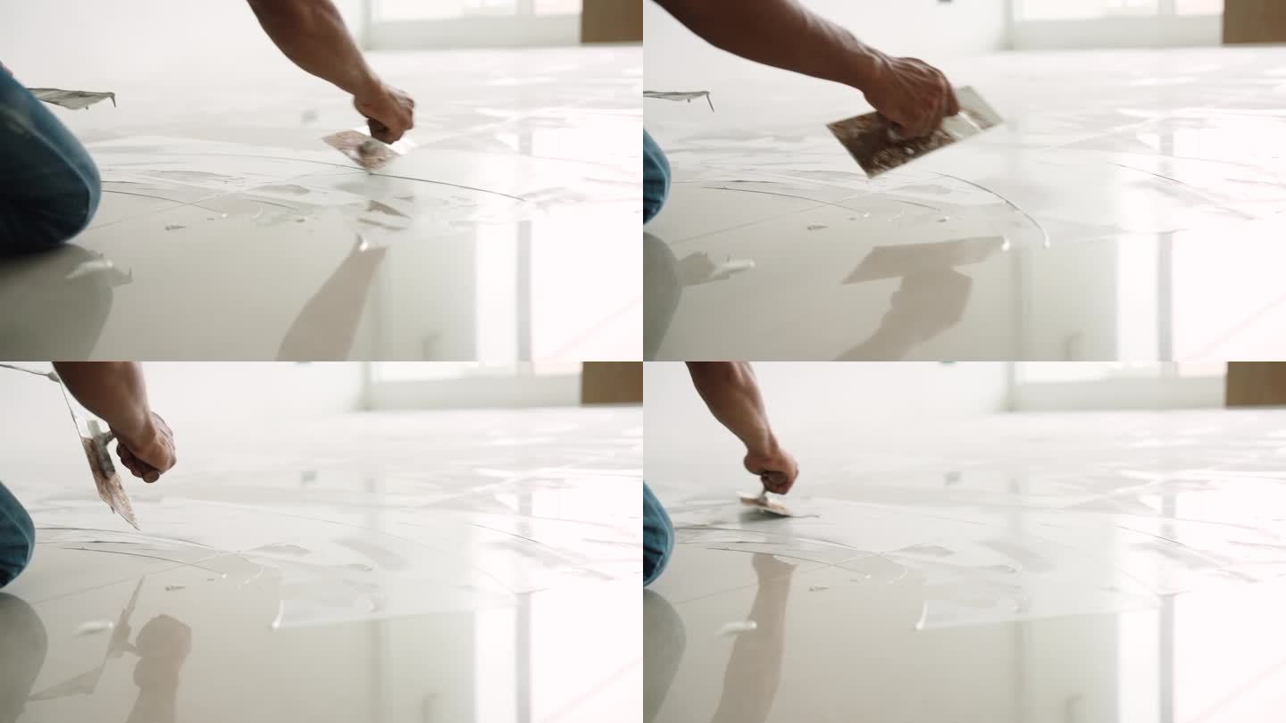 工人用抹灰抹刀在地板上抹灰平整，然后再把强化板铺在地板上