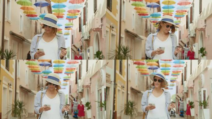 在克罗地亚，一名女游客用信用卡和智能手机在建筑装饰的雨伞下行走
