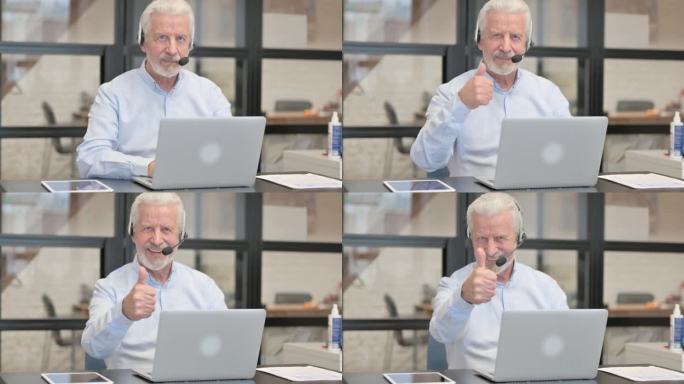 在呼叫中心，一位戴着耳机使用笔记本电脑的老人竖起了大拇指