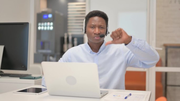 在呼叫中心戴着耳机使用笔记本电脑的非洲人表示反对