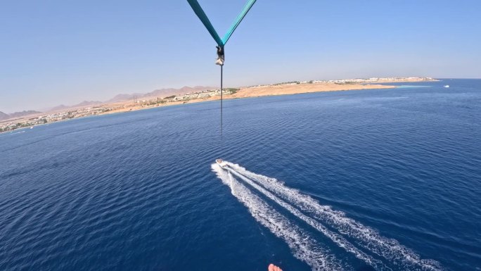 滑翔伞水上娱乐-在埃及红海度假胜地的海边，乘坐降落伞在船上飞行。