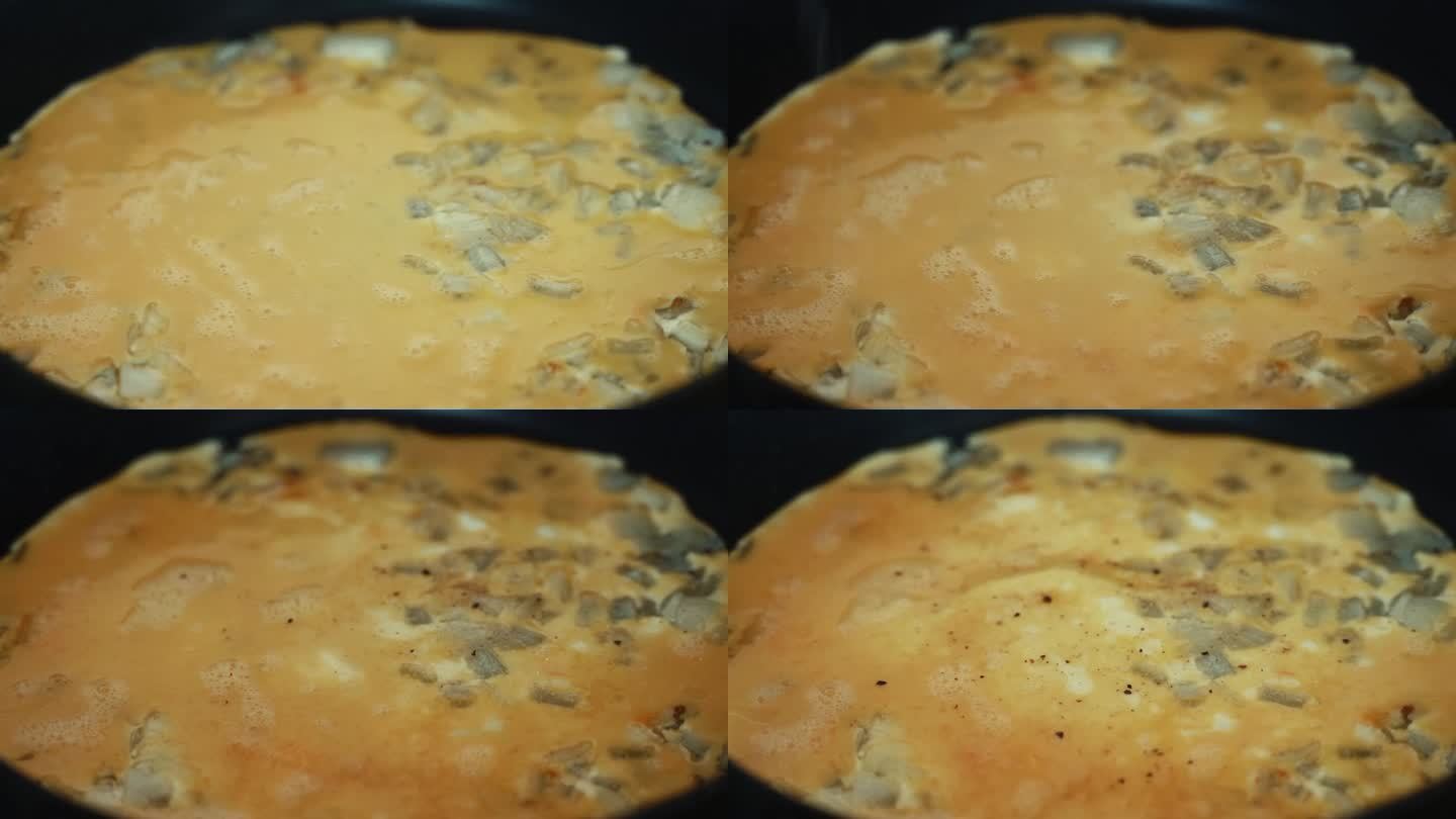 一个延时特写镜头，鸡蛋混合物填满烤洋葱，在黑热的平底锅上翻转煎蛋卷，揉碎鸡蛋，制作早餐4K视频