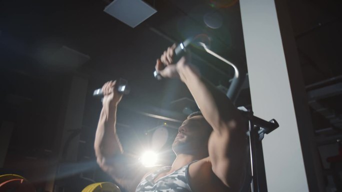 健美运动员在健身房里使用举重机锻炼双手和胸部肌肉