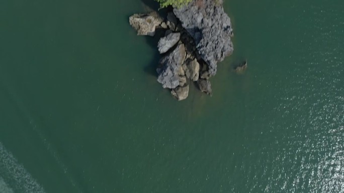 鸟瞰经过马来西亚浮罗交怡海域一个小岩石岛的船只。