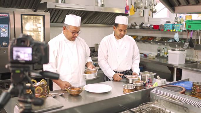两名男厨师正在准备印度菜，用相机记录
