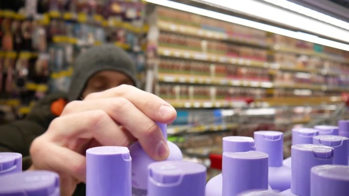 多瓶紫罗兰色洗发水的特写，一位男性买家正在挑选一瓶