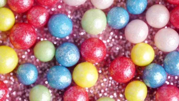 甜甜的糖屑，多色球，微距视频。五彩缤纷的糖屑旋转，装饰糖球的背景