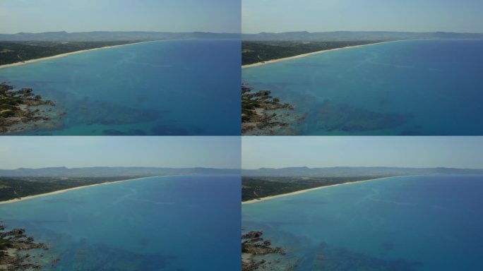 无人机的原始撒丁岛海岸线与充满活力的蓝色海水，岩石海岸，和郁郁葱葱的绿色景观，展示了意大利的自然之美