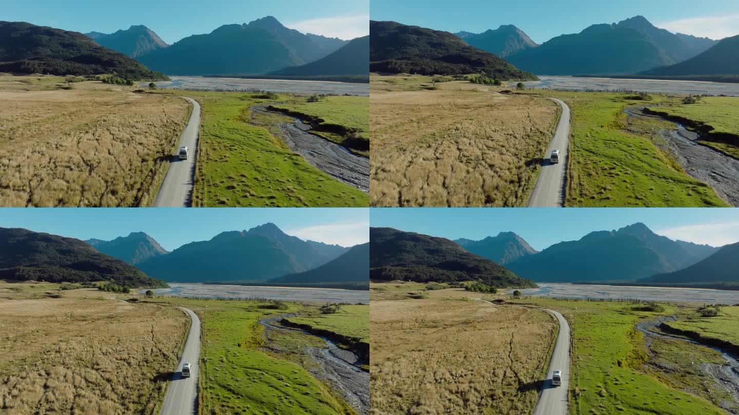 风景优美的鸟瞰图露营车穿过绿色高原崎岖的山地景观探索艾辛格地点从指环王在格伦诺奇，新西兰南岛奥特罗阿