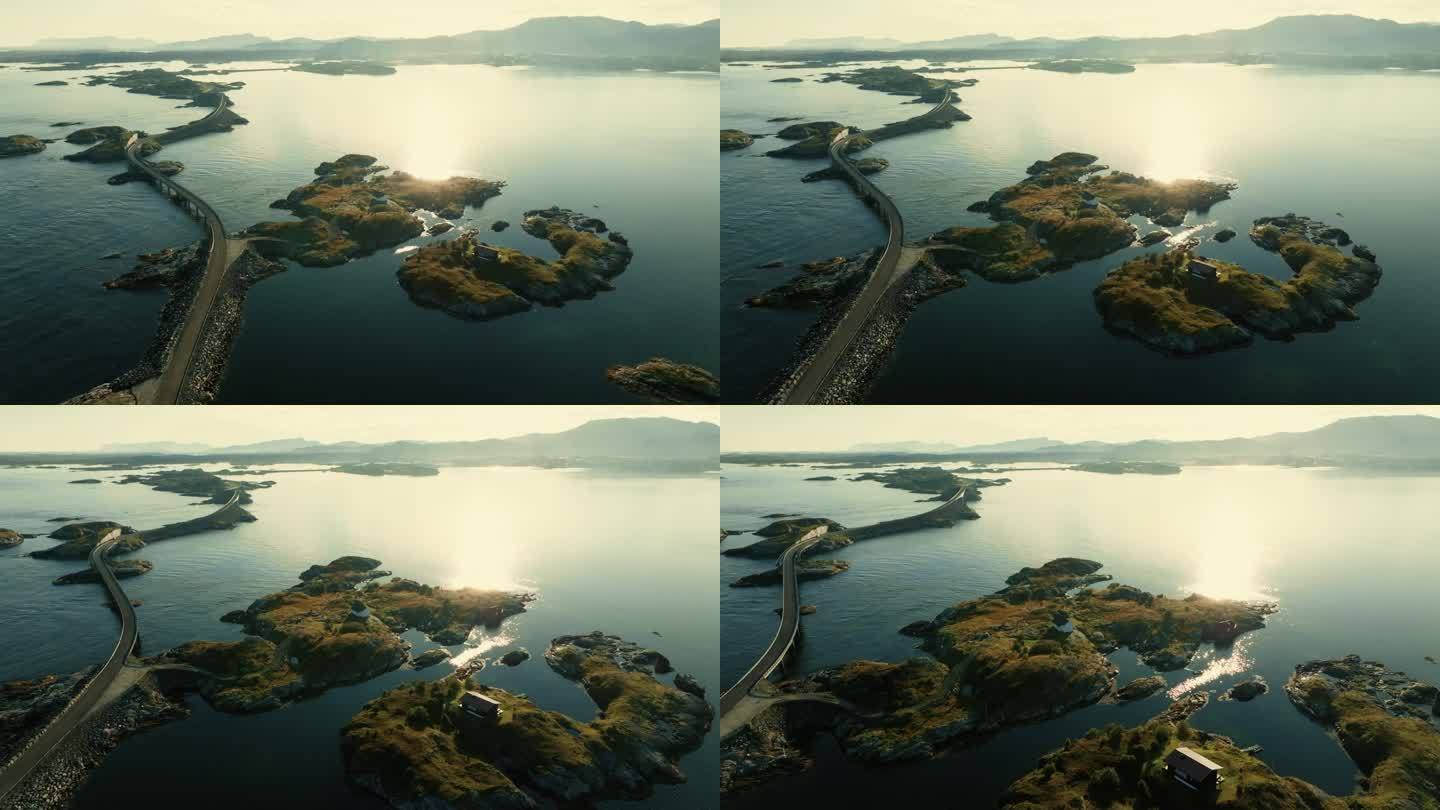 一架无人机飞过大西洋的公路，在明亮的阳光下飞向一个小岛，小岛上的房子坐落在广阔的水面中央