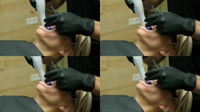 一位牙医医生在给一个小女孩检查时使用3D牙科扫描仪