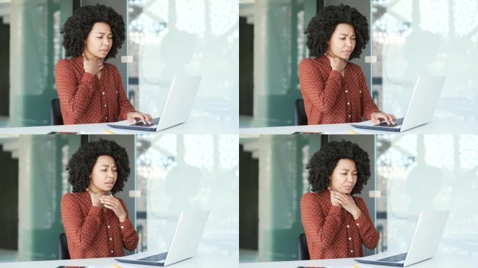 生病的年轻非裔美国女员工在办公室坐着用笔记本电脑工作时喉咙痛