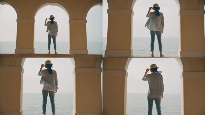 在克罗地亚，戴着遮阳帽的女游客站在海边柱廊的挡土墙上，天空晴朗