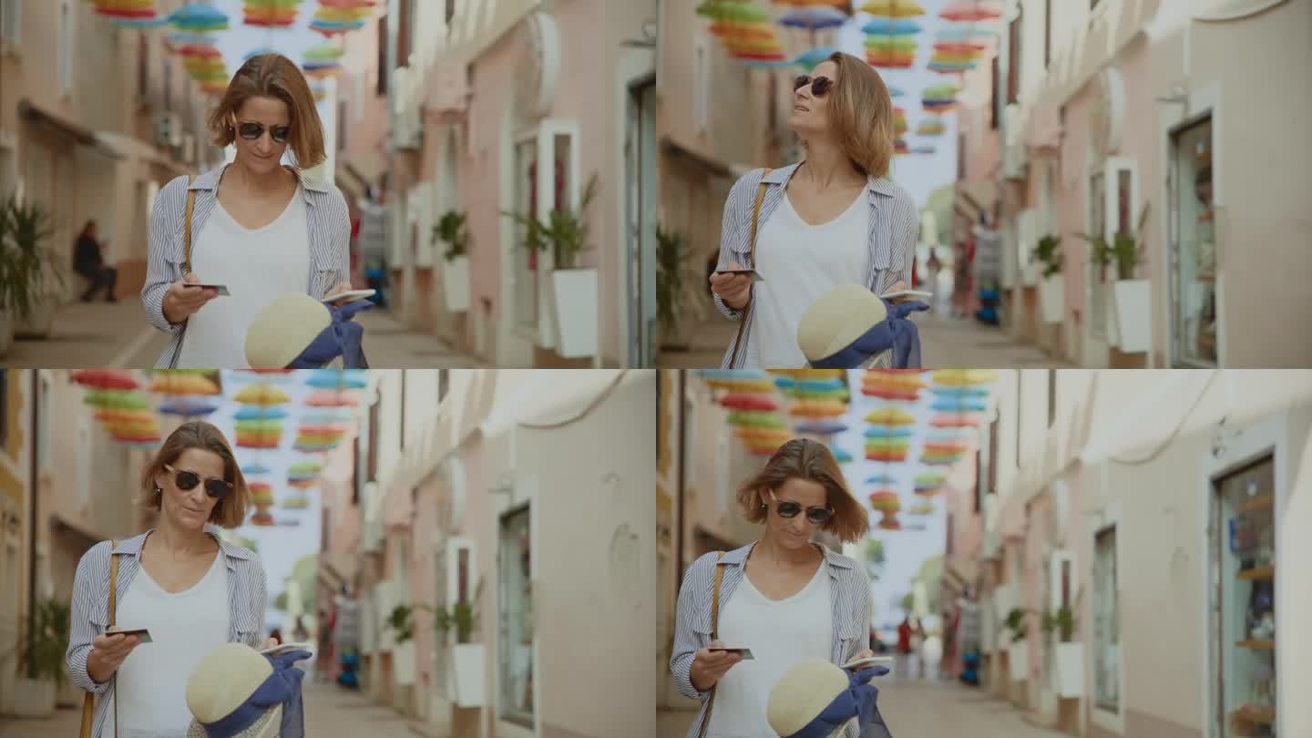 在克罗地亚，一名成年女性游客用信用卡和智能手机在建筑装饰的雨伞下行走