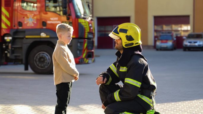 身穿制服的消防员在消防站和一个小男孩在一起