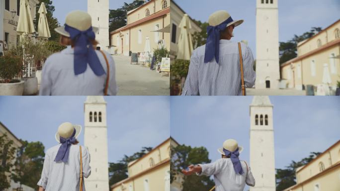 阳光明媚的一天，克罗地亚罗维尼，一名兴高采烈的女游客一边朝大教堂塔楼走去，一边吃着冰淇淋