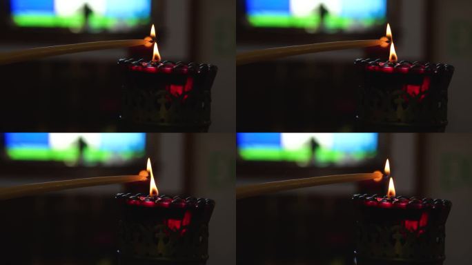 燃烧的红色蜡烛与闪烁的火焰在黑色背景前面的蜡烛被点燃的微距镜头