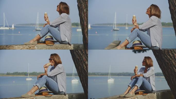 克罗地亚的一名女游客在港口的挡土墙上享受着冰淇淋