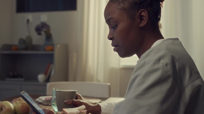 非裔美国医生边吃早餐边浏览智能手机