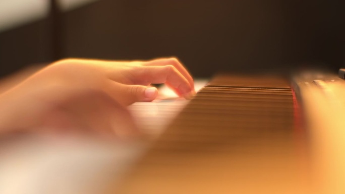一个小学生弹钢琴的特写镜头。快乐的年轻亚洲女孩学习和练习钢琴。有选择性的重点。