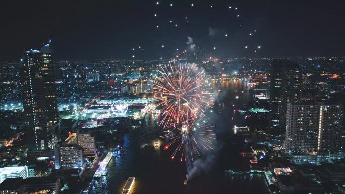 多色烟花在城市和摩天大楼上表演，庆祝夜晚的灯光、河流和曼谷大桥