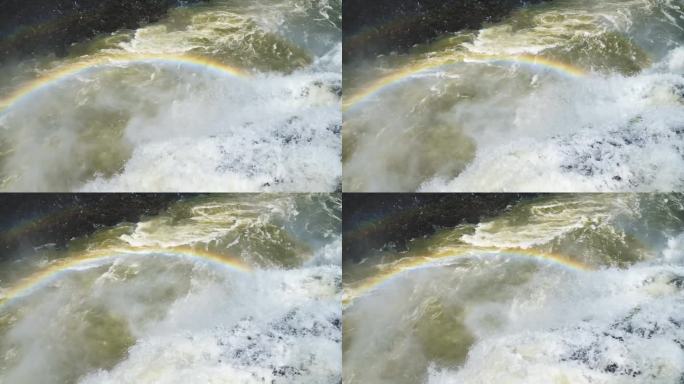 在阳光明媚的伊瓜苏瀑布，阿根廷，南美洲，五彩缤纷的水从悬崖边缘飞入彩虹覆盖的大跳水池