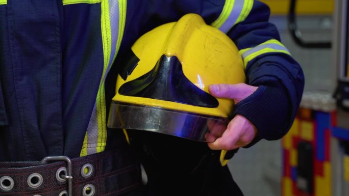 手持头盔的消防员站在车站，近距离拍摄