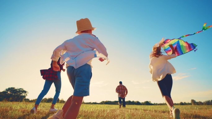 回头看幸福的一家人一起欢欢喜喜地奔跑在夏日的田野草地上。休闲活动，漫步大自然。孩子和父母。运动的运动