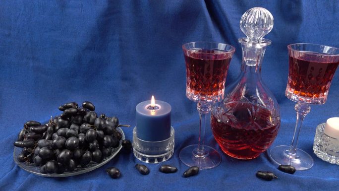 水晶醒酒器和酒杯与葡萄酒，水晶盘与葡萄在蓝色缎面背景