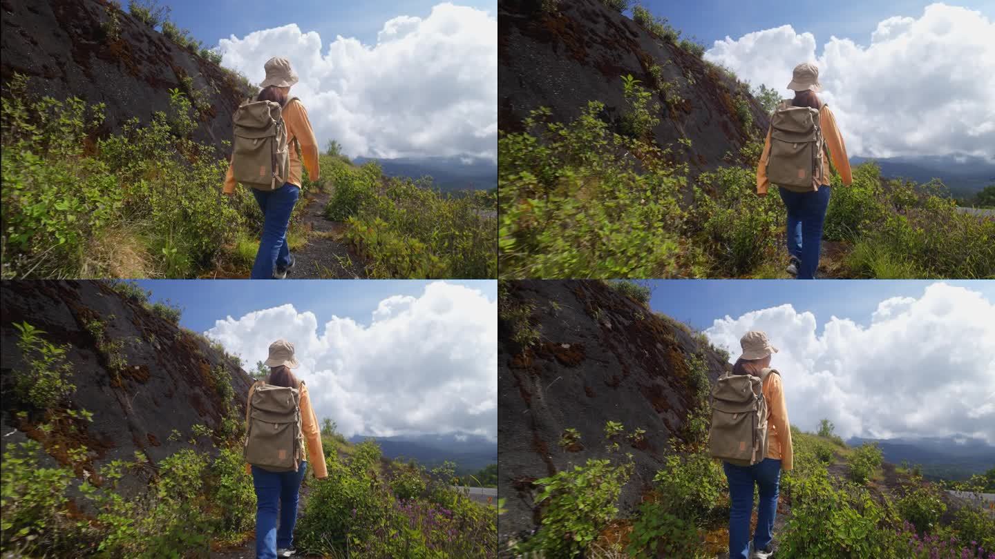 徒步旅行者有吸引力的快乐的年轻女孩背着背包在山上徒步旅行，周围都是令人惊叹的风景