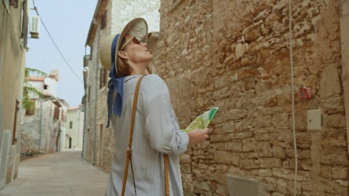 在克罗地亚，一名女游客手持地图走在住宅楼中间的街道上