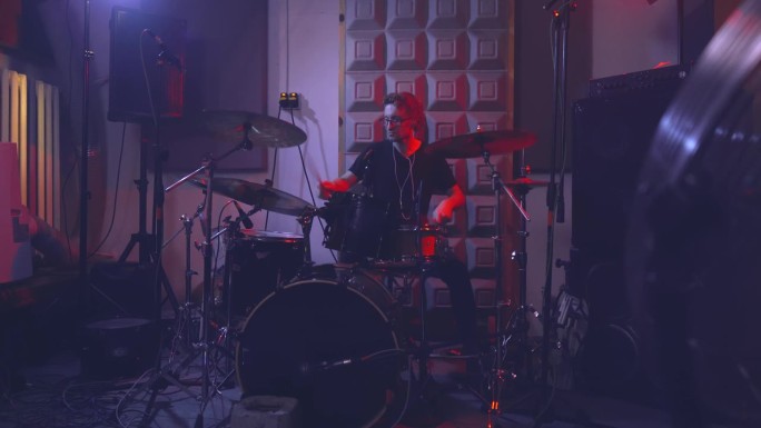 摇滚乐队的鼓手在排练室里演奏架子鼓。