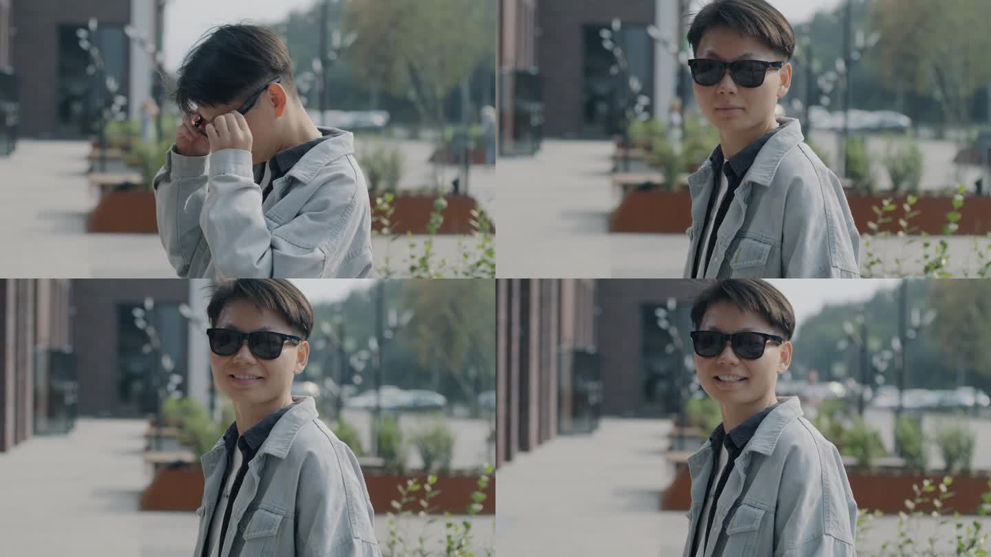 一个快乐的亚洲男人戴着时髦的太阳镜，在城市街道上对着镜头微笑