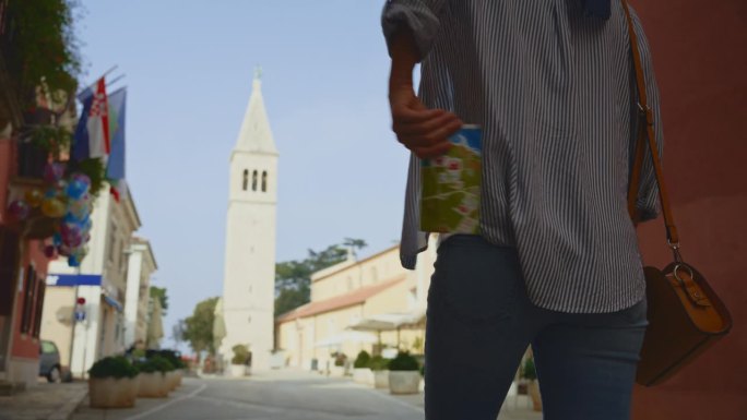 克罗地亚罗维尼，一名女游客从口袋里掏出地图，走向教堂塔