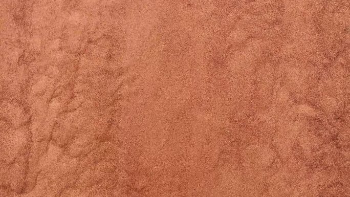 背景是沙漠中沿着沙丘流下的红色沙子。沙子倾泻而下