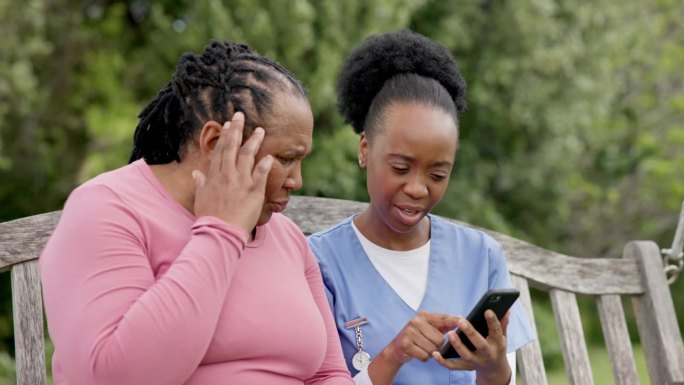 老年人，妇女和护士在花园里用电话与失忆，痴呆或阿尔茨海默氏症进行交流。老人、黑人和看护者拿着智能手机