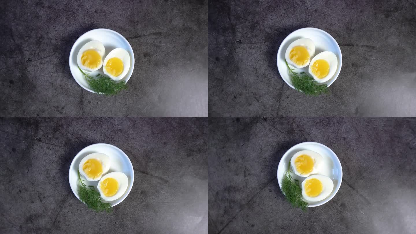 两个半煮鸡蛋与新鲜的香草在一个白色的碟子-俯瞰4K